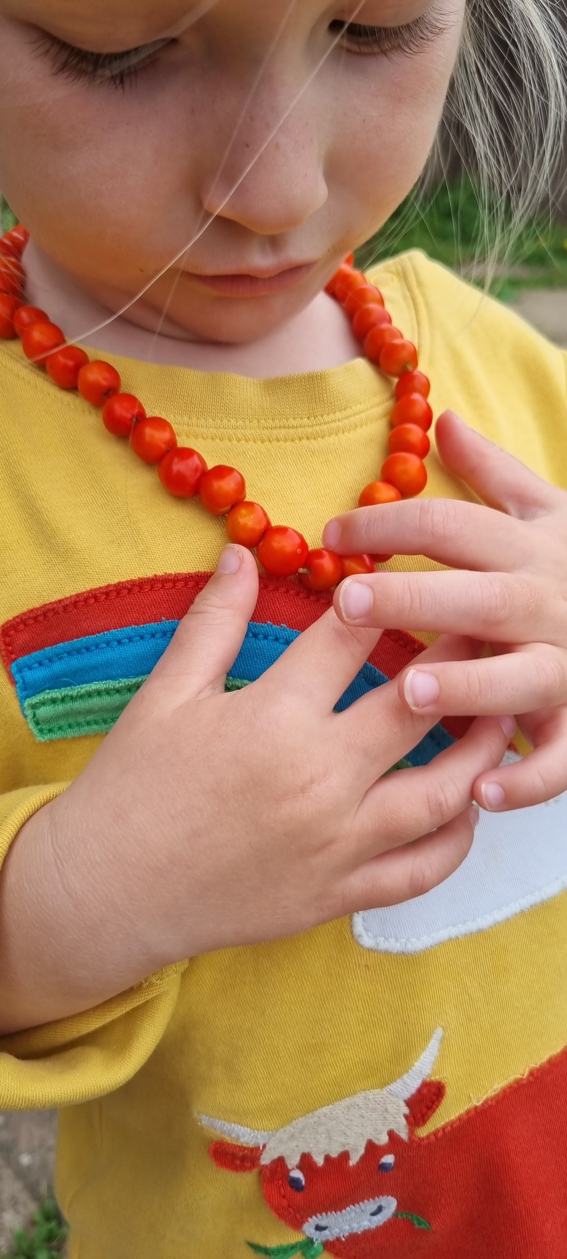 A child wearing the finished rowan berry necklace