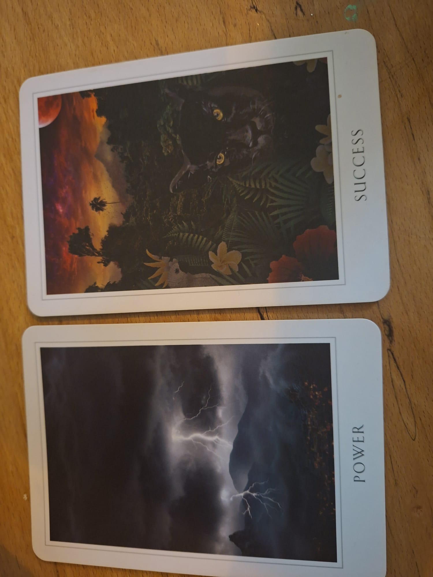 Two oracle cards, Power and Success, on a wooden table