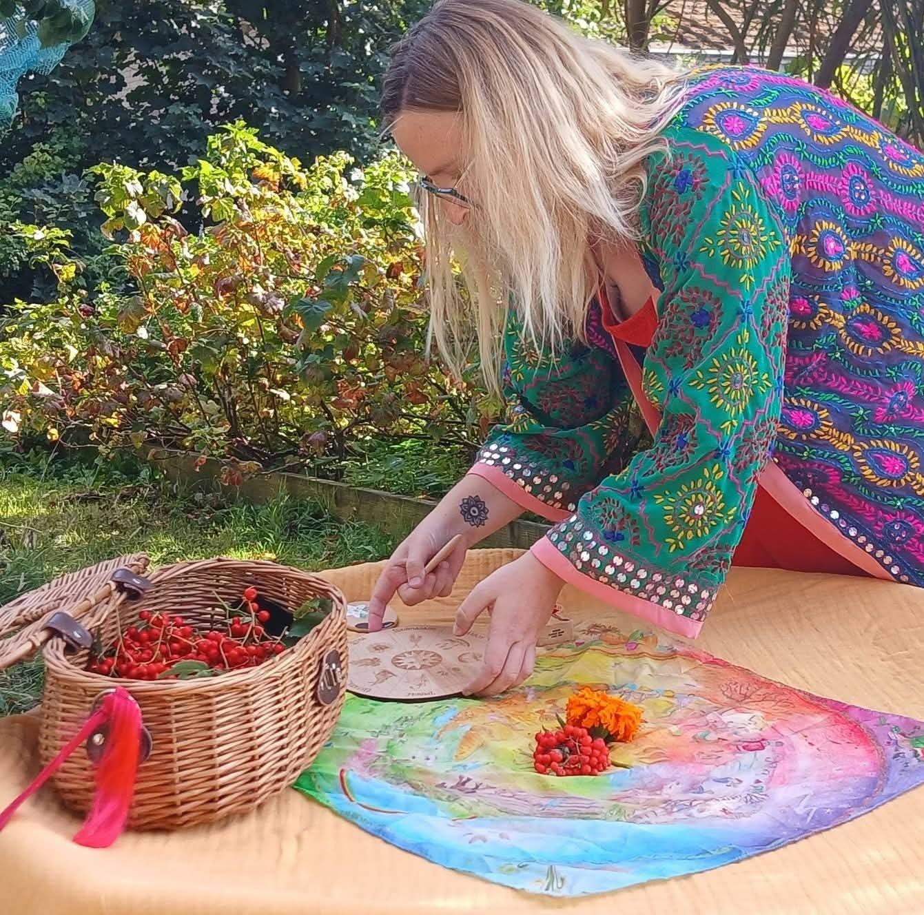 Katy Swift outdoors with a hand-painted Wheel of the Year
